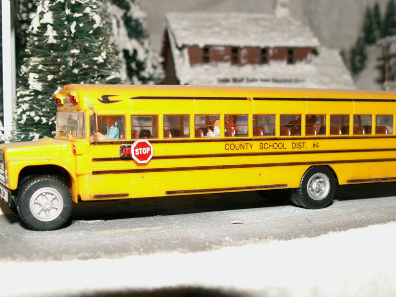 A school bus takes kids home from school on an icy mountain road.