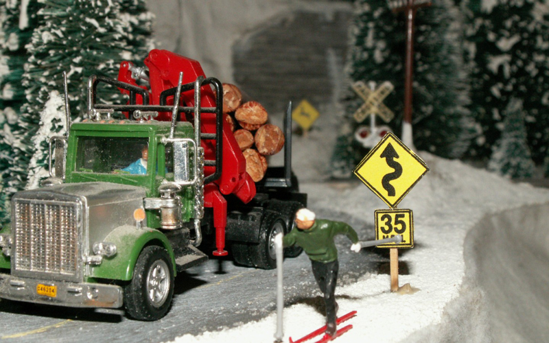 A log truck passes a cross country skier on a snow covered road 