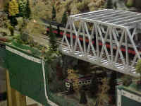 A close-up photo of the WNYSSA trestle module as an American Models Alco PA-PB-PA locomotive in New Haven livery crosses the trestle and a trolly appears on the lower track.