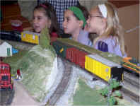 Three young girls are watching the trains on the RASG modular layout.  Photo by Bob Welsh.