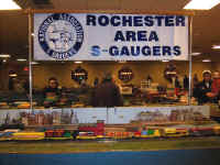 The circus train is passing below the Rochester Area S-Gaugers banner.