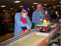 Dave  Blaufuss of Dave's S Gauge Trains looks on while a young guest operates the log loader.