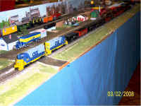 A pair of CSX GP35s pulls a unit train of coal cars past the yard modules.