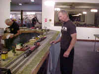 Chuck Smith starts the break down process while Rick Isrealson watches a NYC train make a last lap or two around the layout.