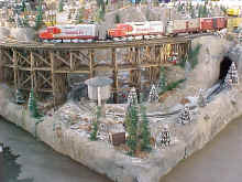Santa Fe locomotives cross trestle at a corner of the display.