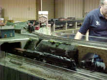 An Amrican Flyer 4-8-4 steam locomotive emerging from the final corner module of the display.